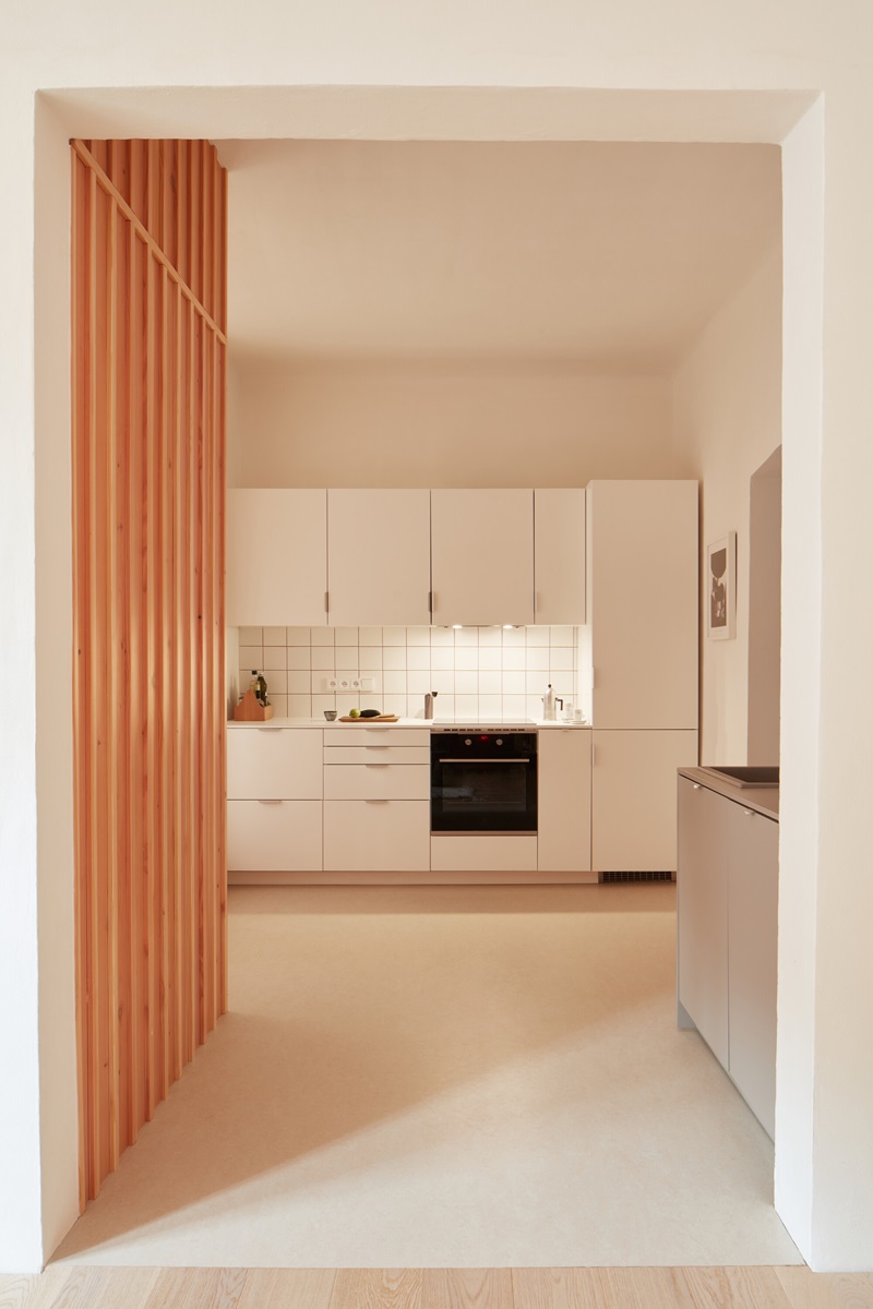 Plus-One-Architects- Vršovice-Apartment: cocina blanca y suelo marmoleo
