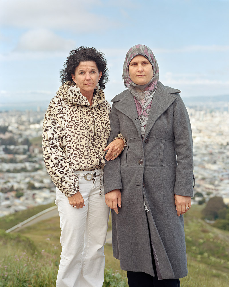 Revela't. Imagen de dos mujeres posando con la ciudad de fondo.