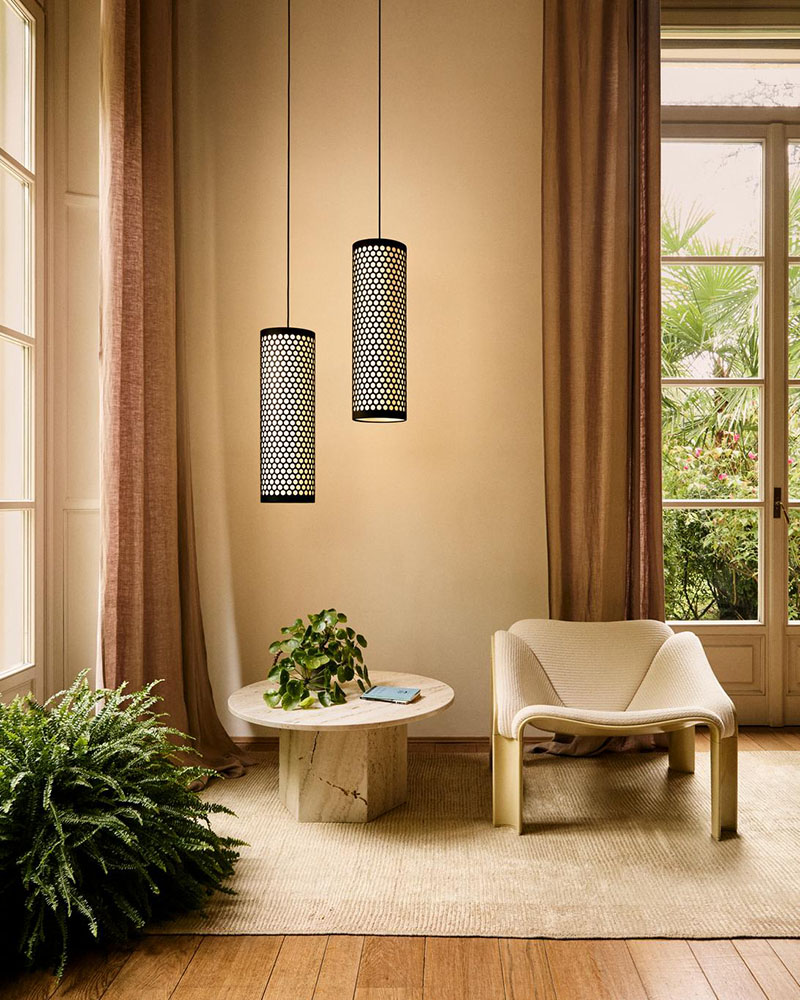 La Gubi F300 Lounge Chair de Pierre Paulin situada en un interior doméstico, acompañada de una mesa redonda y lámparas cilíndricas