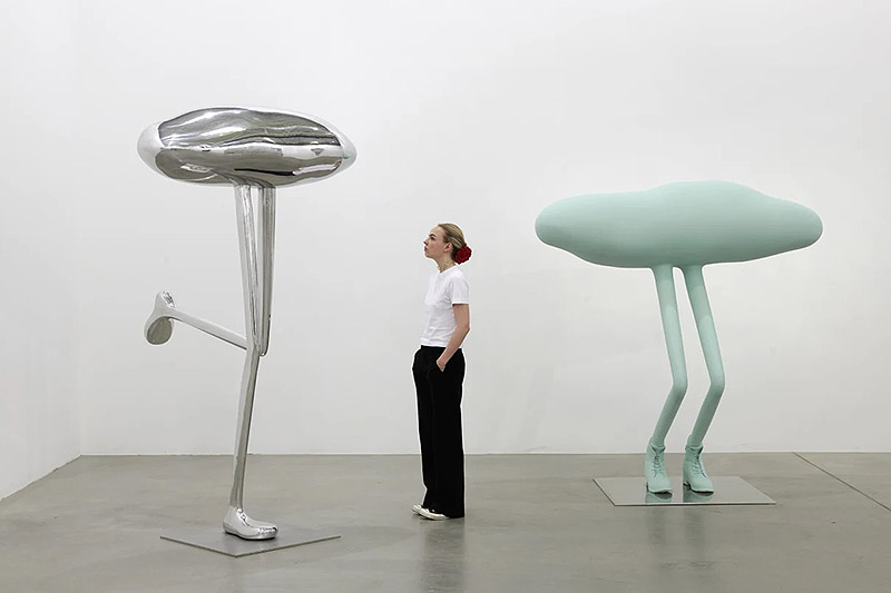 Erwin Wurm, exposición Mindset - una mujer observa esculturas de formas redondeadas con patas alargadas