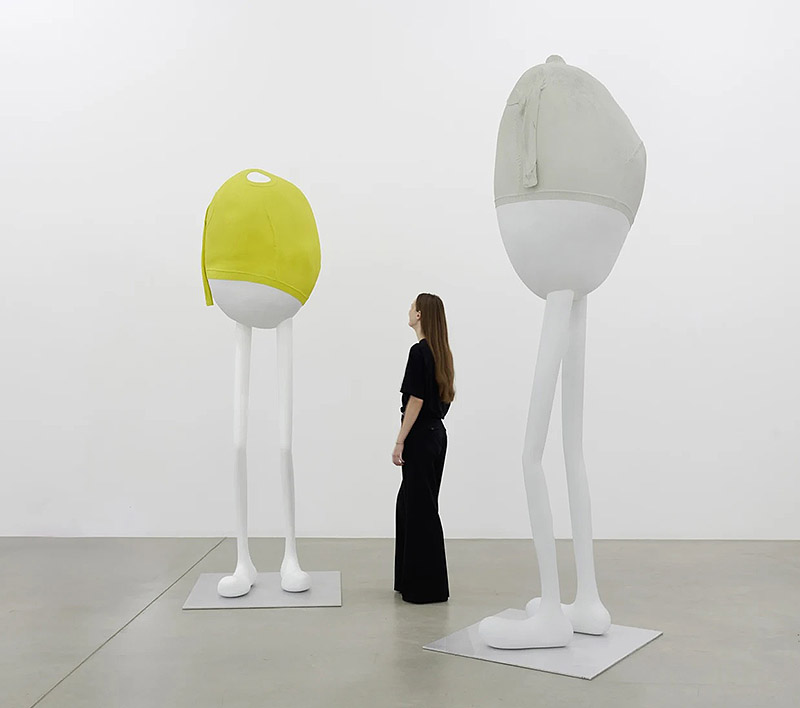 Erwin Wurm, exposición Mindset - una mujer observa esculturas de formas redondeadas con patas alargadas