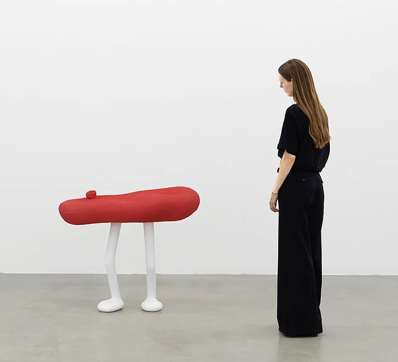 Erwin Wurm, exposición Mindset - una mujer observa esculturas de formas redondeadas con patas alargadas