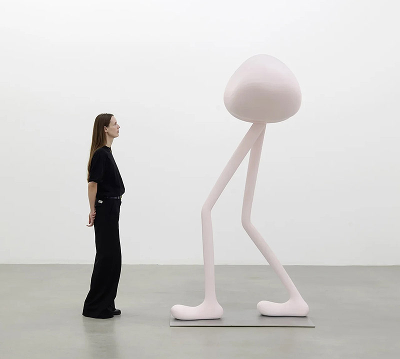 Erwin Wurm, exposición Mindset - una mujer observa esculturas de formas redondeadas con patas alargadas