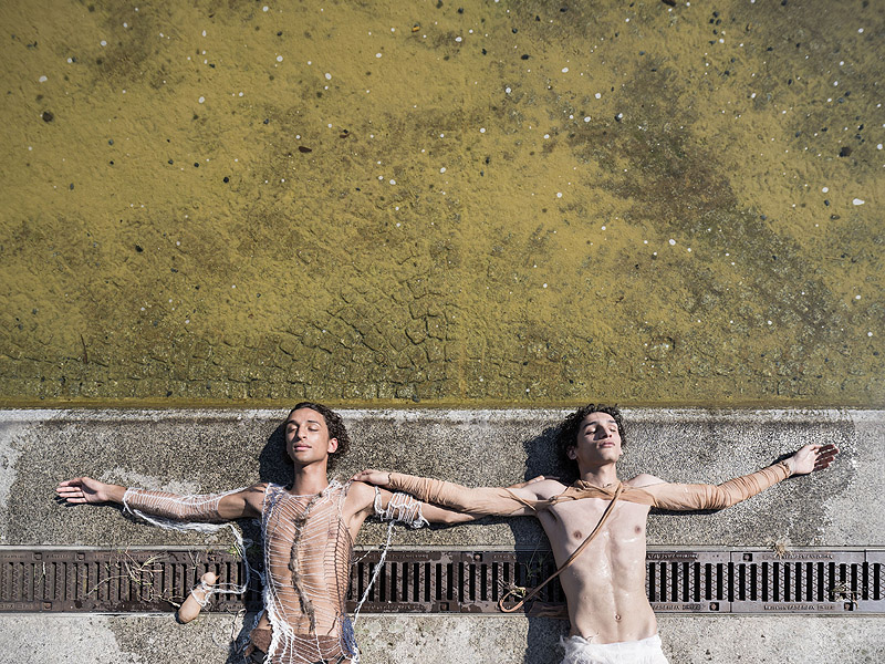 Dos performers con el torso descubierto apoyados sobre una obra