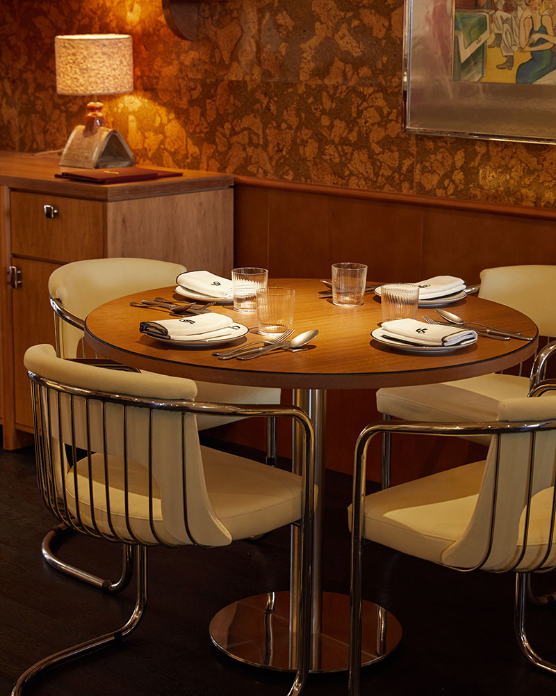 Casa Fiero equipa un comedor con mesa redonda, sillas de estructura metálica y lámpara de sobremesa