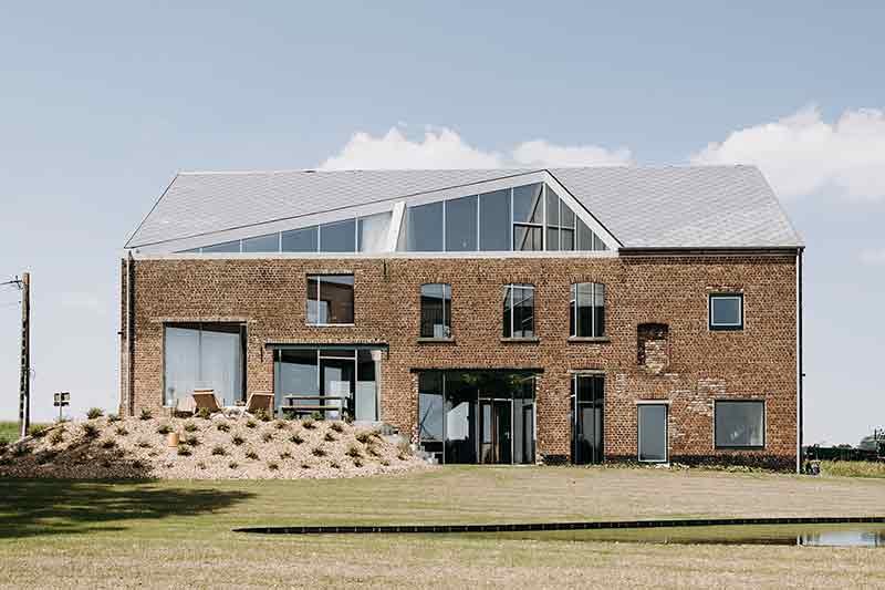 Fachada principal de Casa Lyco, proyecto de Oyo Architects, con la silueta original del antiguo granero y nuevas aberturas integradas
