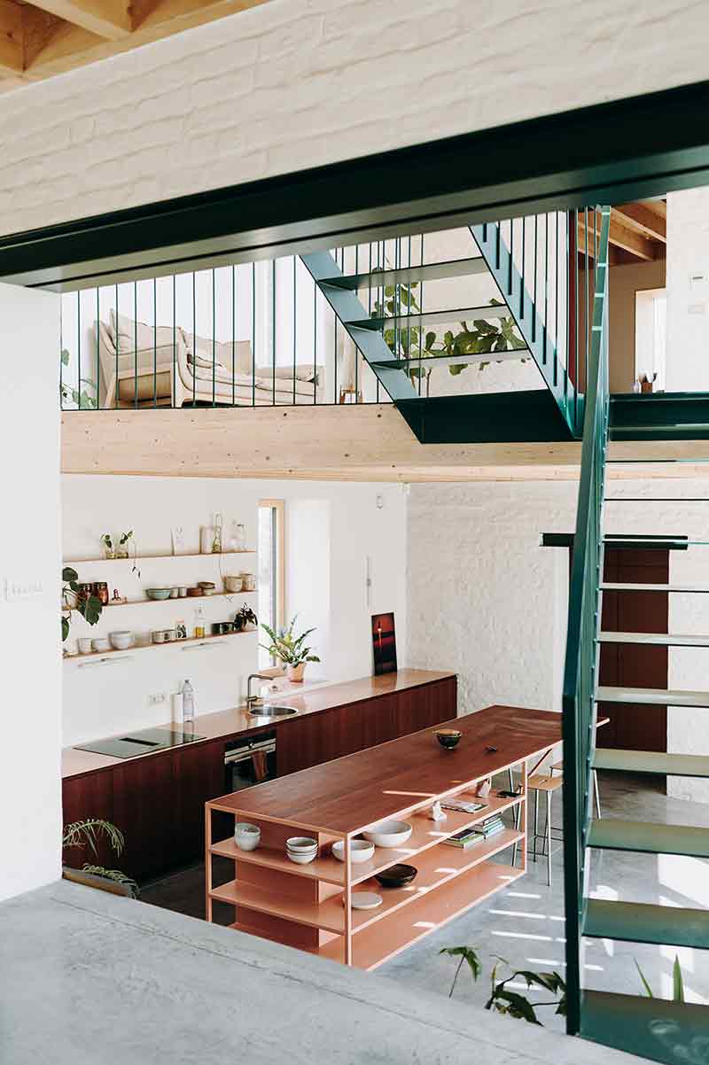 Conexión entre niveles interiores de Casa Lyco, donde Oyo Architects incorpora una escalera metálica y doble altura