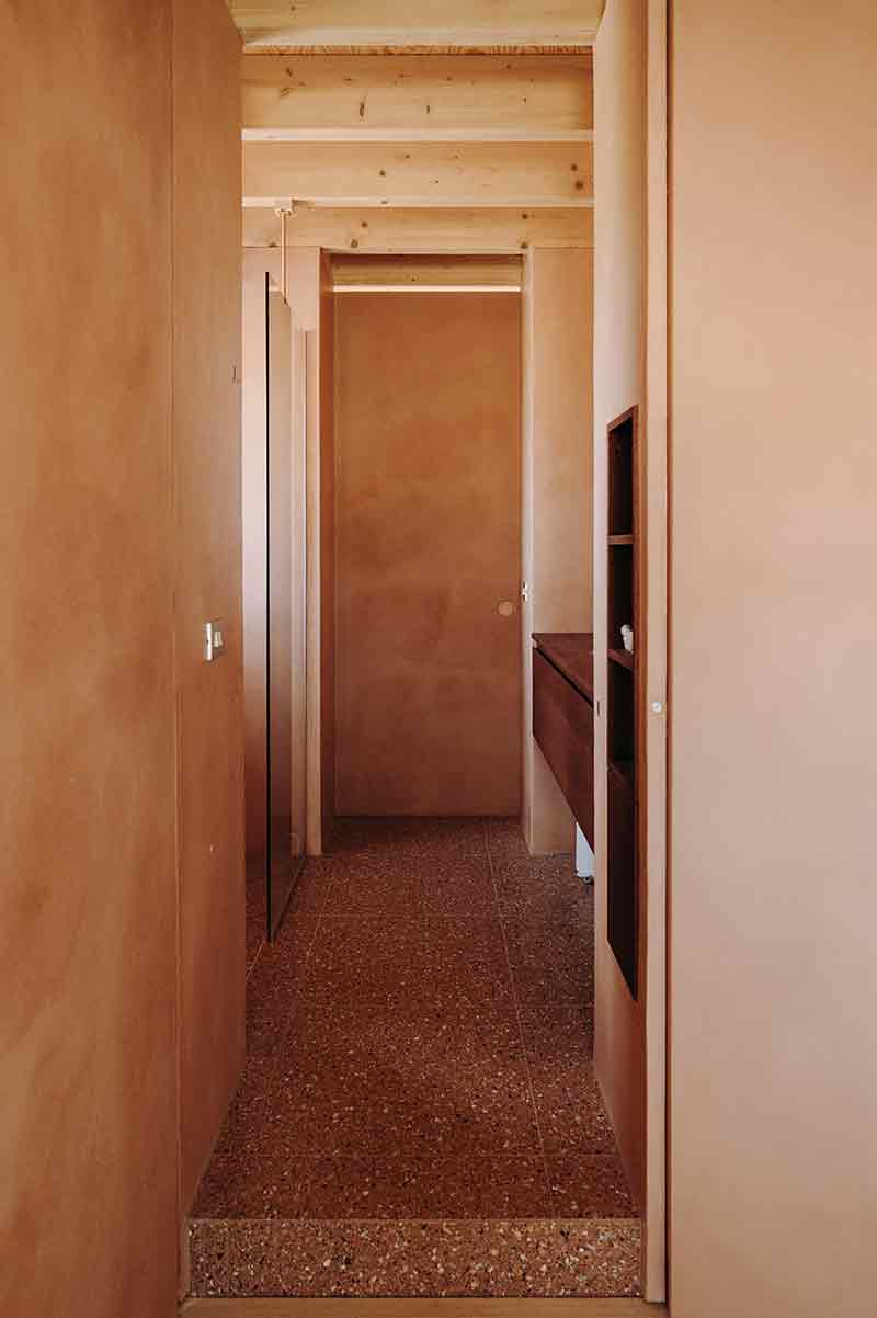Pasillo interior de Casa Lyco, proyectado por Oyo Architects, con revestimientos en marga y carpinterías integradas