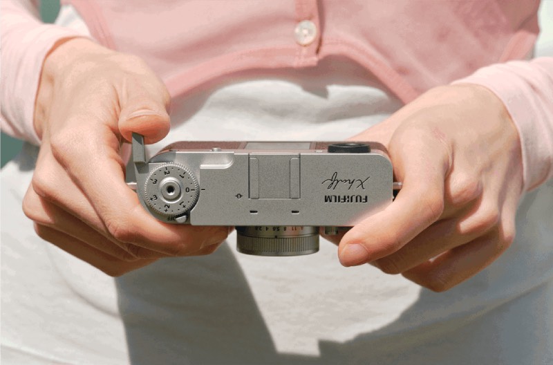 Fujifilm X half: primer plano de la las manos de una mujer de piel clara pasando la foto del carrete de la cámara digital compacta Fujifilm X half.