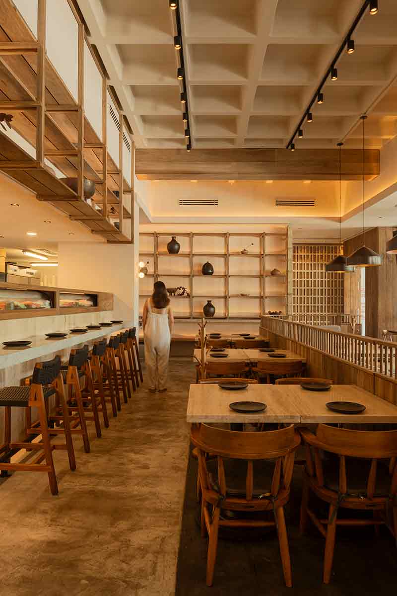 Vista longitudinal del salón de SC | Nido Cancún por Neutro Estudio con barra al fondo y estantería frontal