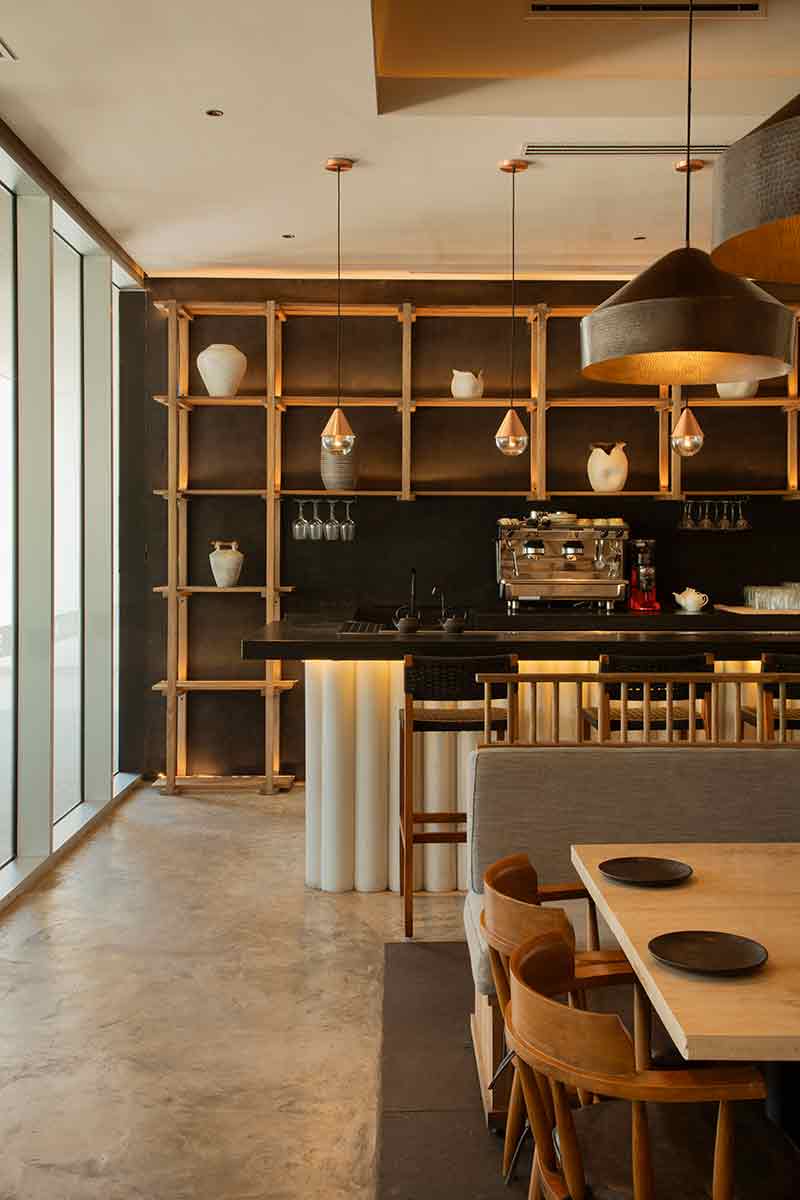 Barra de bebidas en SC | Nido Cancún diseñada por Neutro Estudio con estantería en madera y fondo oscuro