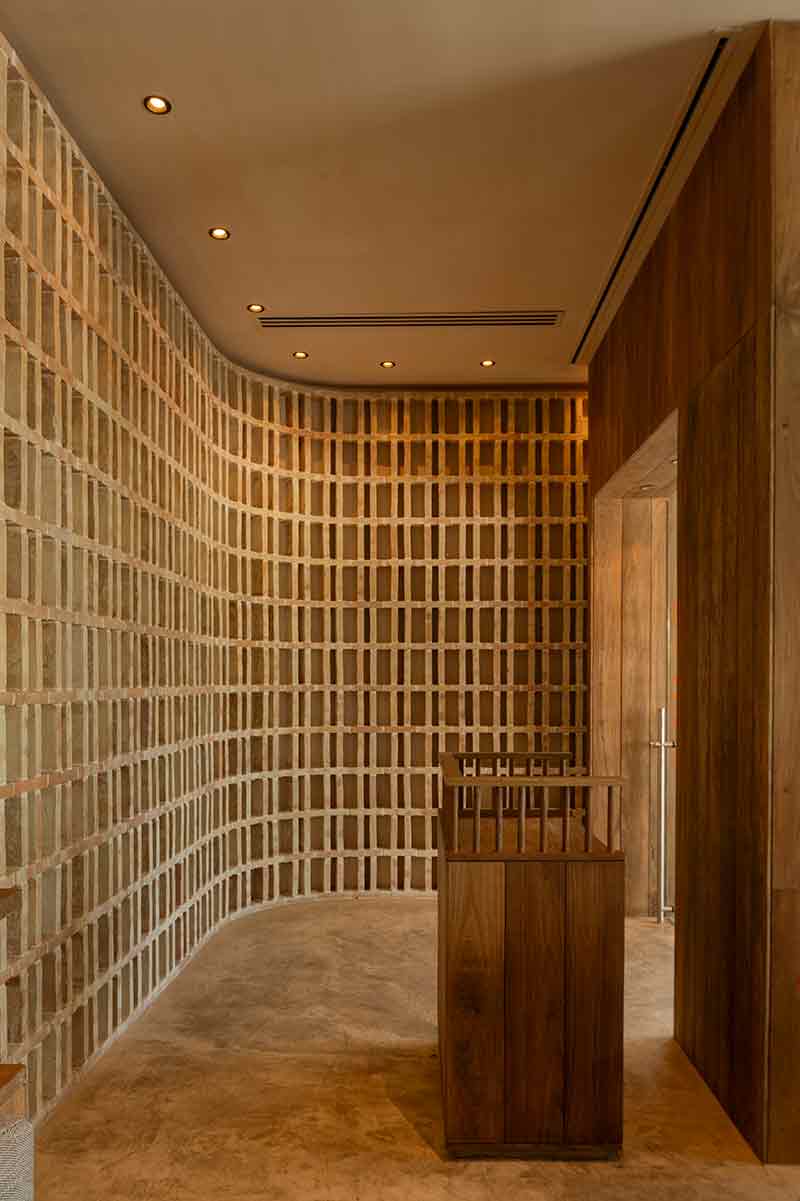 Acceso de SC | Nido Cancún proyectado por Neutro Estudio con celosía curva de barro y mobiliario de recepción