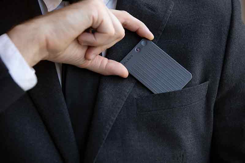 Plaud Note: primer plano del bolsillo superior de la chaqueta de un traje oscuro en el que un chico de piel clara guarda una grabadora Plaud Note.