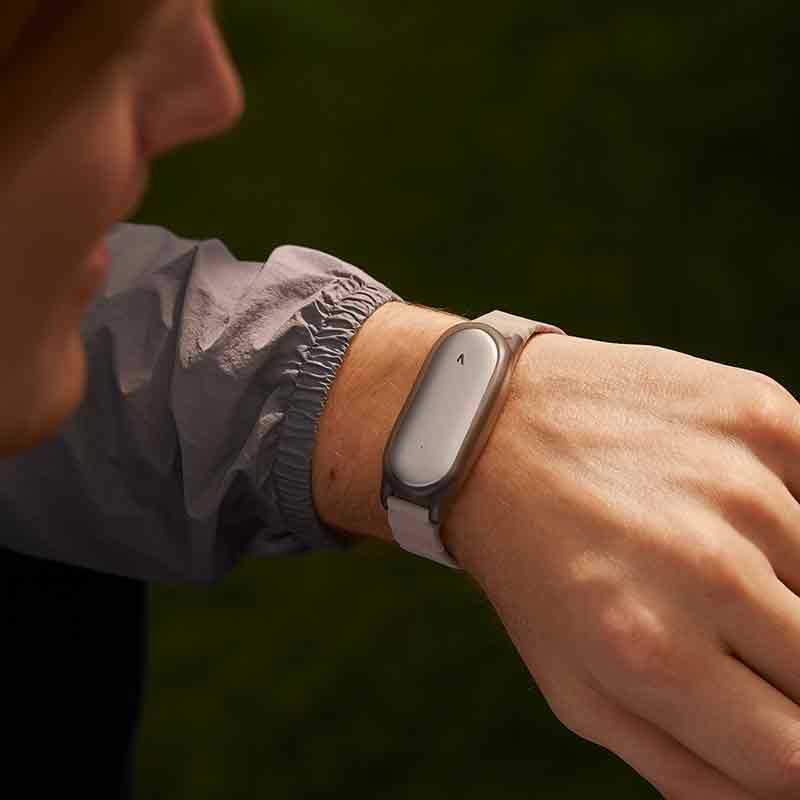 Plaud Note: primer plano de la mano de una persona que lleva la grabadora Plaud NotePin en pulsera.