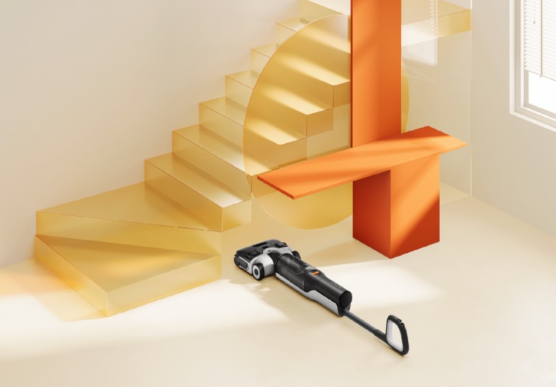 Roborock: un robot de limpieza Roborock negro en el suelo bajo el hueco de unas escaleras de color amarillo transparente.