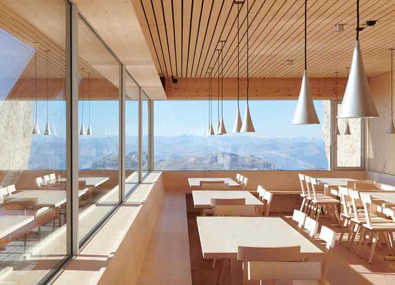 Comedor del Santnerpass con mobiliario de madera y ventanales al paisaje alpino