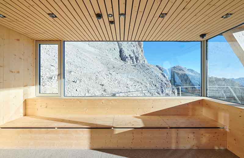 Sala del Santnerpass con bancos de madera frente a ventanales de gran formato