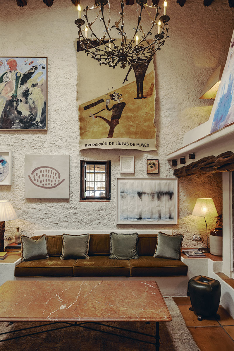 Soho Farmhouse Ibiza: salón con sofá verde, mesa de mármol y paredes con obras de arte