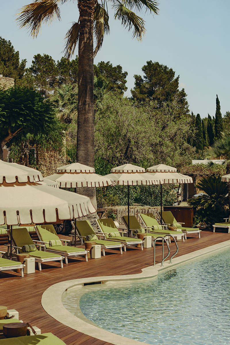 Soho Farmhouse Ibiza: área de piscina con hamacas verdes y sombrillas blancas