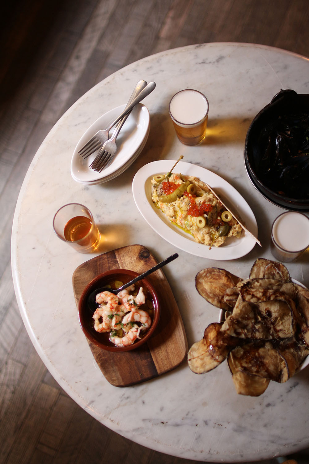 Mesa servida con gambas, ensaladilla, mejillones y cerveza en Tapas Lobito Barcelona
