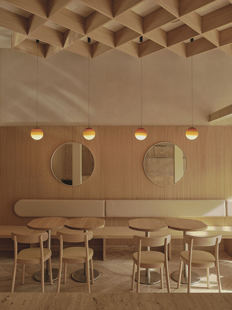 Vista del área de mesas y espejos circulares en la Heladería Regma por Zooco Estudio