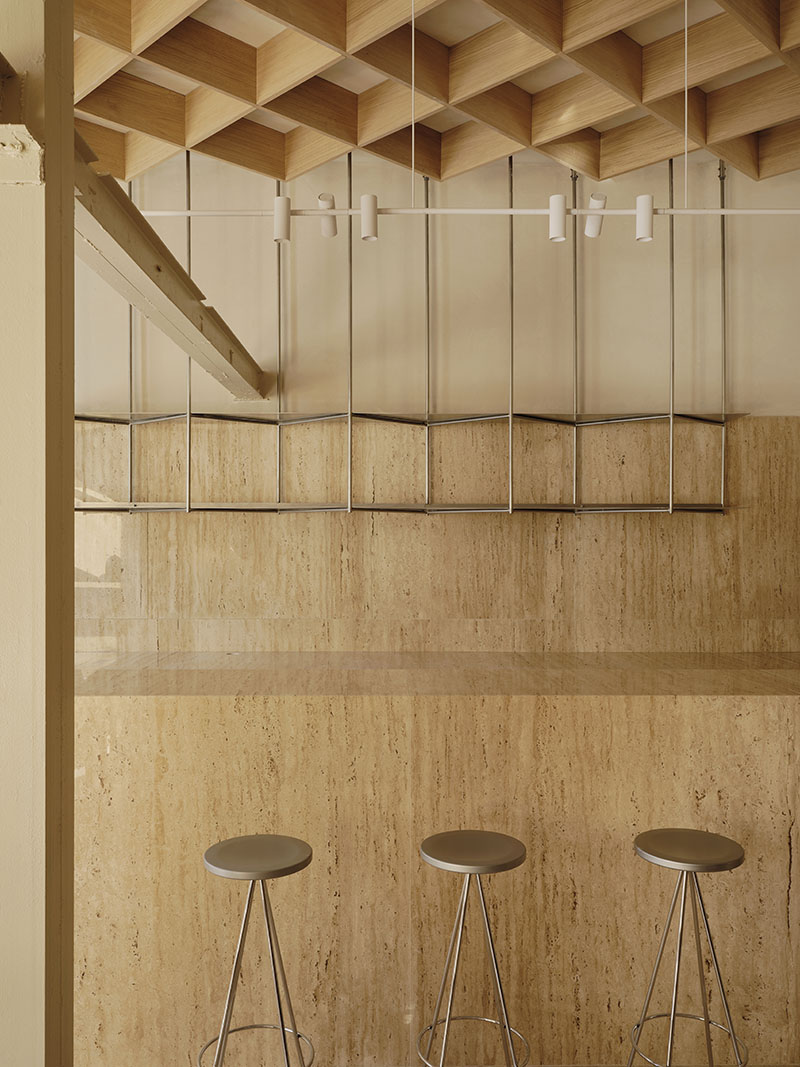 Barra de mármol travertino con taburetes metálicos en la Heladería Regma diseñada por Zooco Estudio