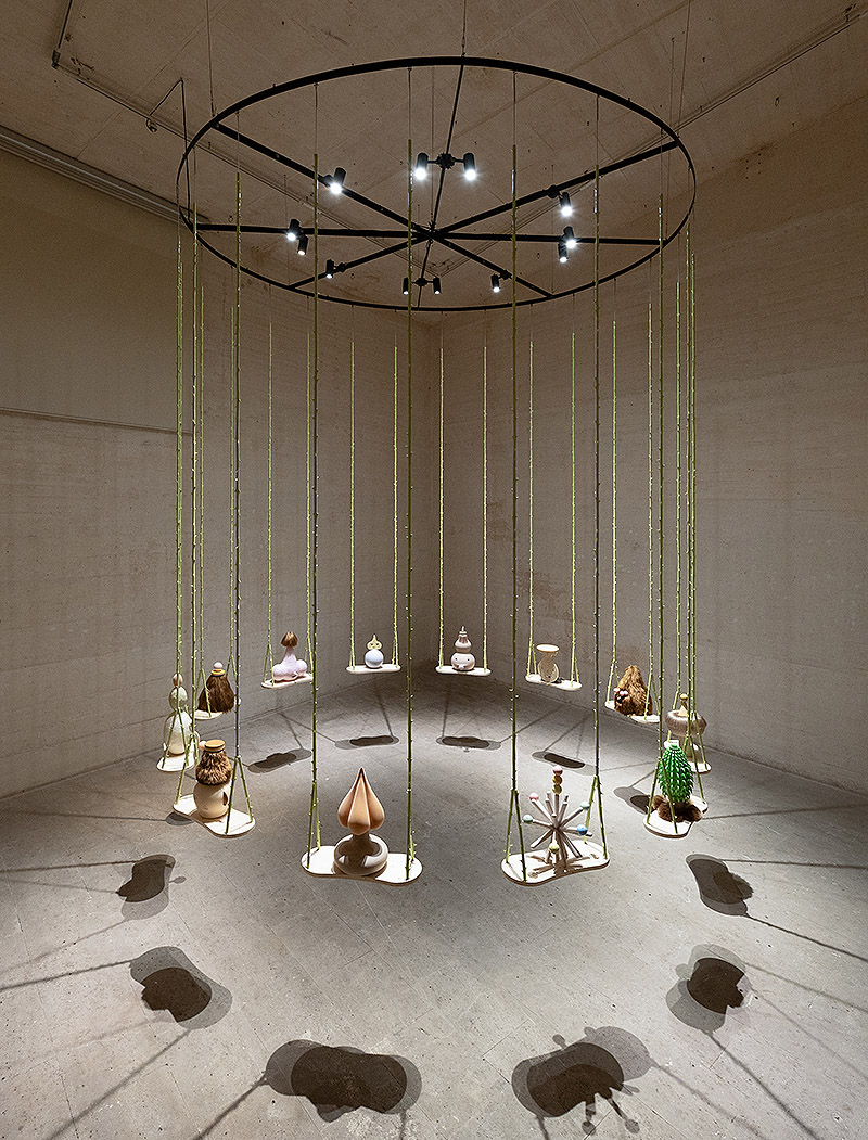 Grip Face - vista de la instalación en la fundación Joan Miró de Mallorca - 12 columpios en círculo en los que hay pequeñas estatuillas, una en cada columpio