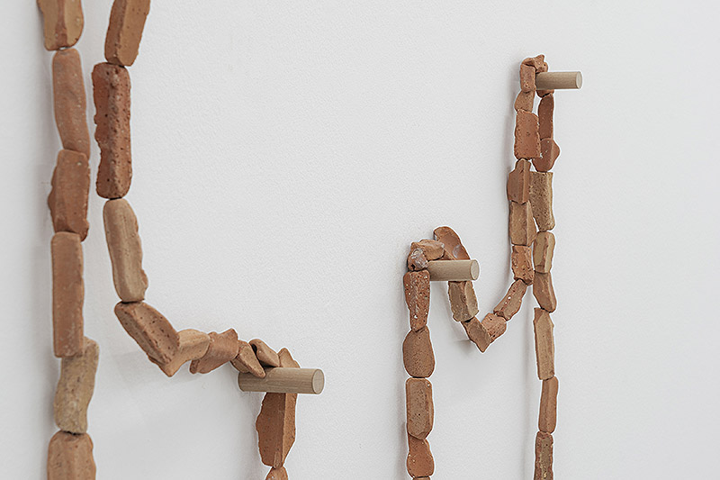 Oro tejido con Paja - vista de la exposición con esculturas por las paredes y el suelo