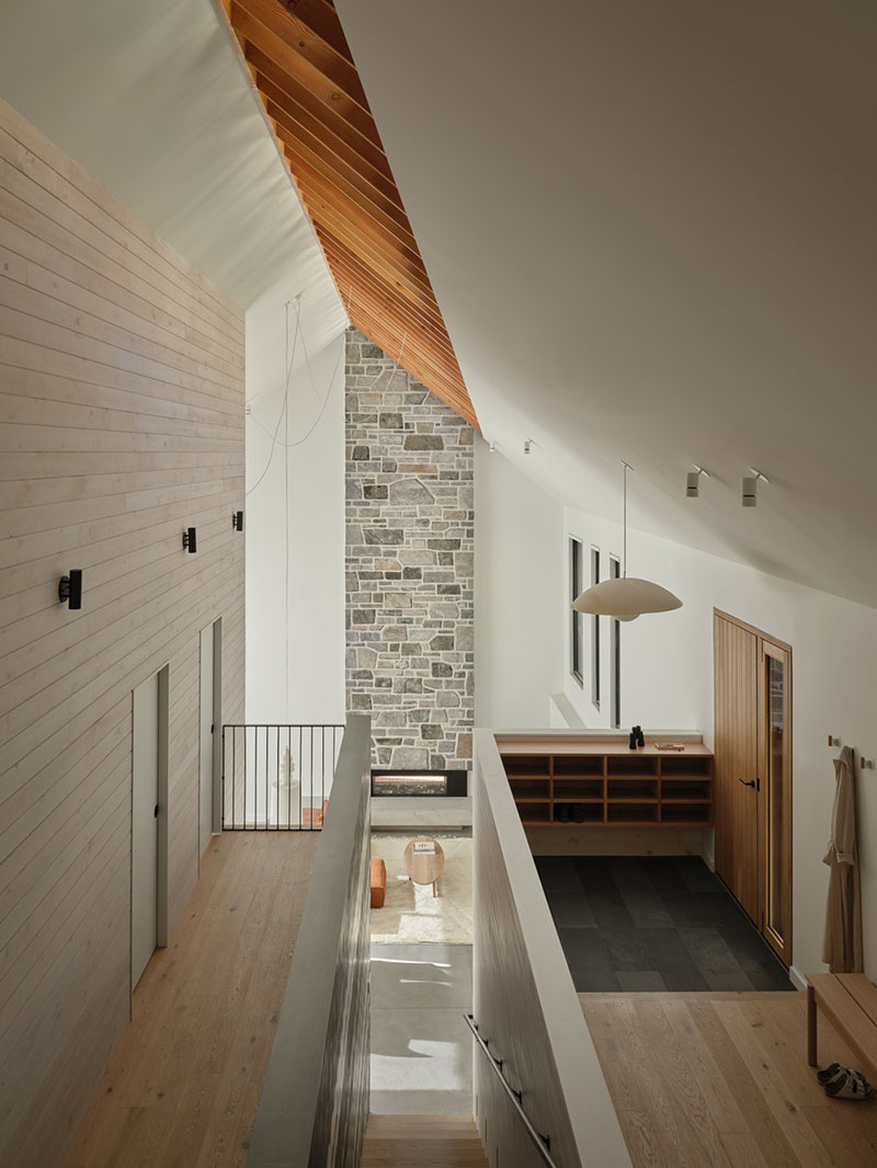 Pasillo superior de Barbora Vokac Taylor Architect con chimenea de piedra y techos inclinados