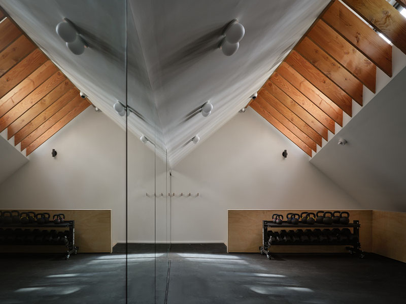 Gimnasio de Barbora Vokac Taylor Architect en el altillo con techos a dos aguas