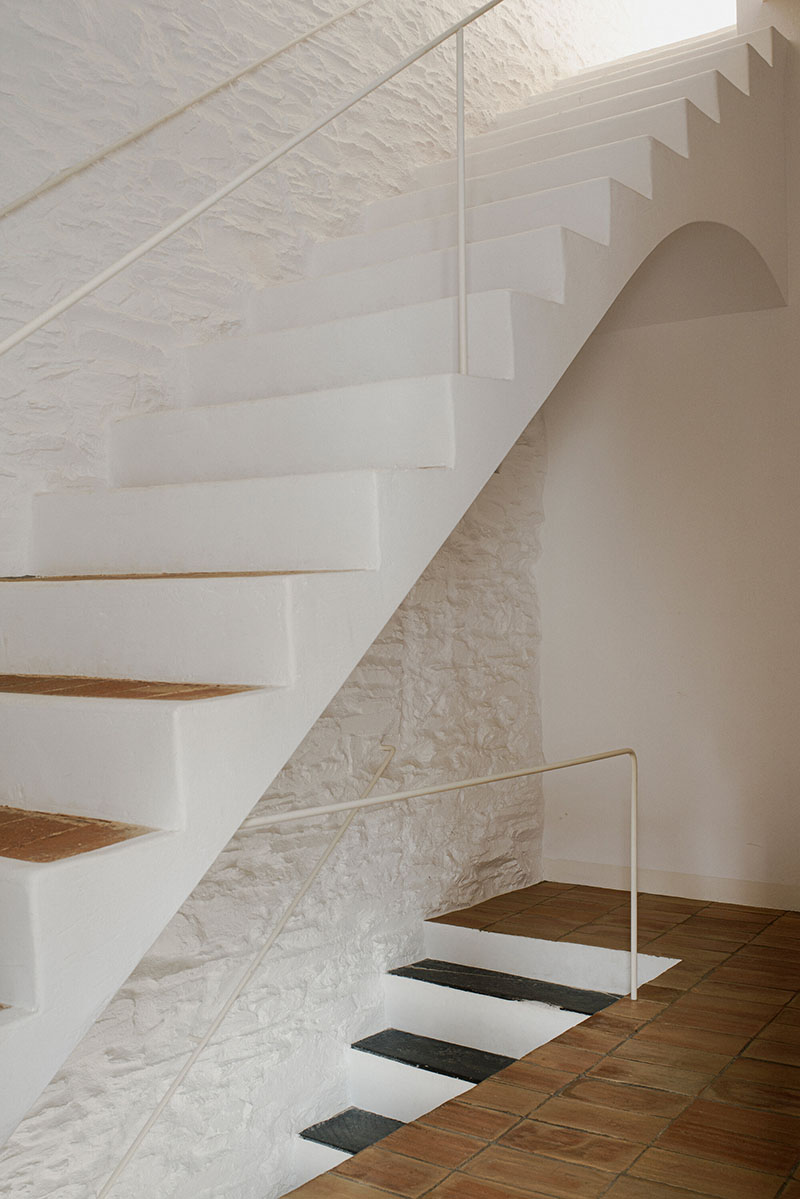 Escalera blanca sobre muro de piedra en la obra de Bea Portabella y Jordi Pagès