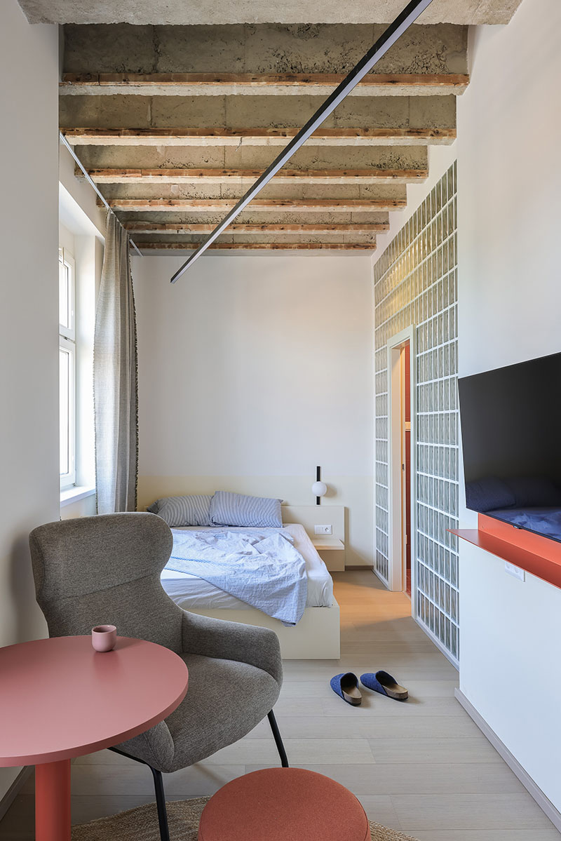 Dormitorio del Metropol con techo expuesto y tabiques de vidrio diseñado por Beed Architekti