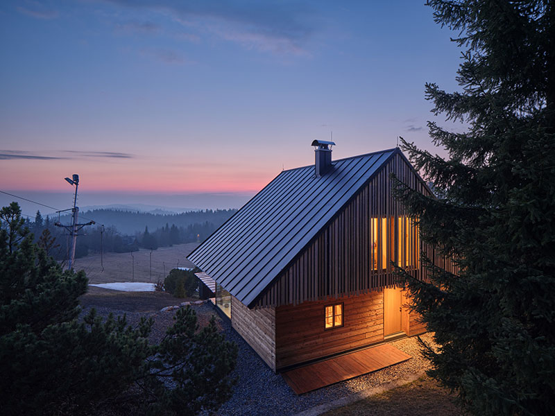 Fachada de la casa rural diseñada por Senaa al anochecer con iluminación interior encendida