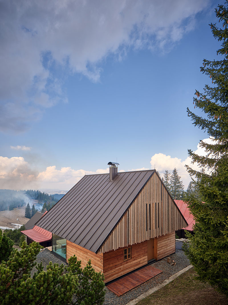 Vista exterior diurna de la vivienda de Senaa con cubierta metálica inclinada y revestimiento de madera