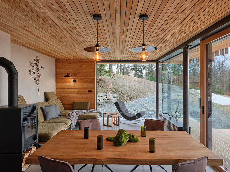 Sala de estar y comedor en planta baja de Senaa con ventanales panorámicos y mobiliario de madera