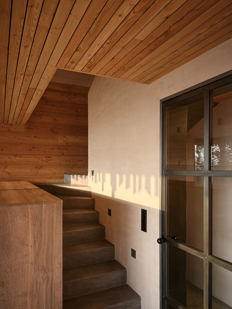 Escalera interior de Senaa con acabados en madera y barandilla en muro cerrado