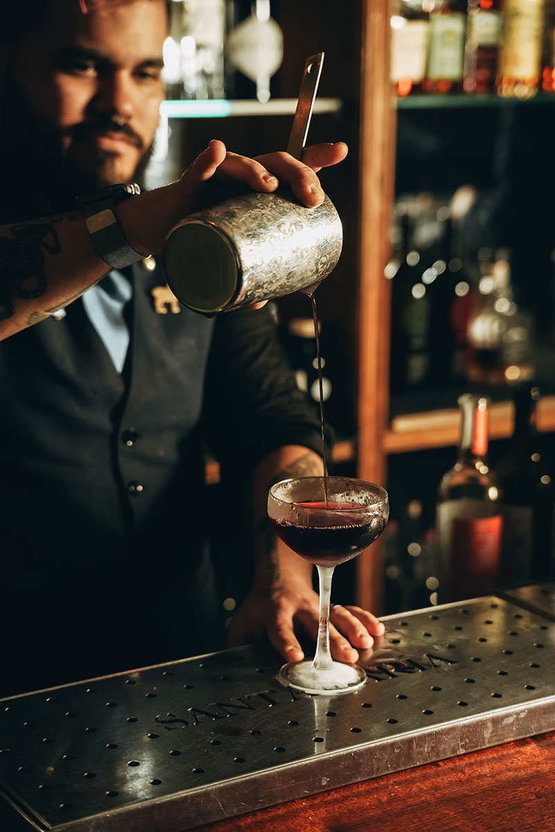 Coctelería Santamaría nueva carta: Barman vertiendo un cóctel en copa de cóctel en la barra
