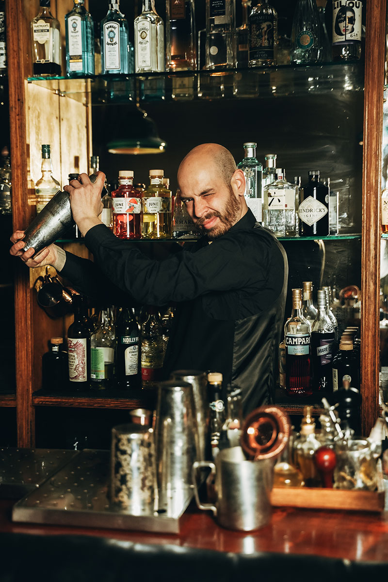 Coctelería Santamaría nueva carta: barman agitando una coctelera frente a la estantería de licores