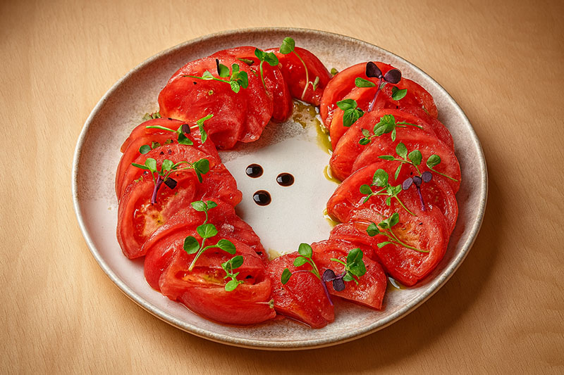 El Patio de LaTomata. una plato con su receta más simple, tomate pelado y con aceite de albhaca