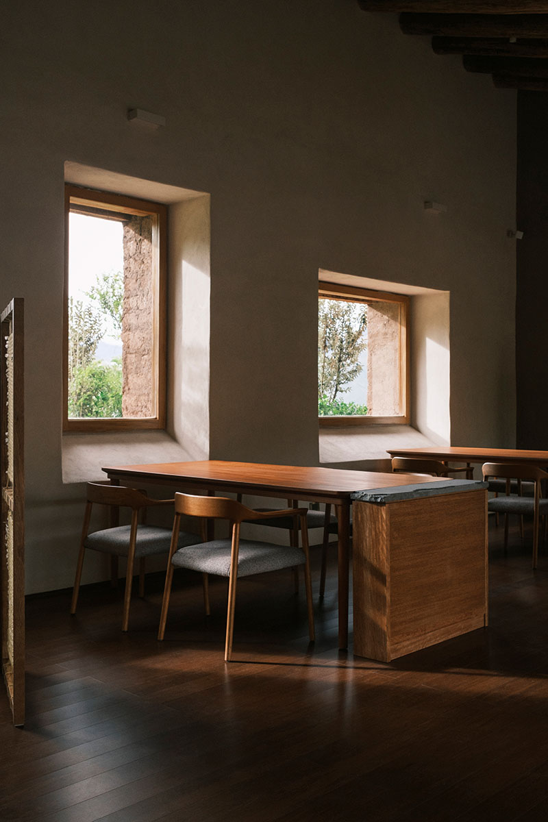 Interior del restaurante Mil intervenido por Estudio Soroche con mesas de cedro orientadas hacia las ventanas de adobe