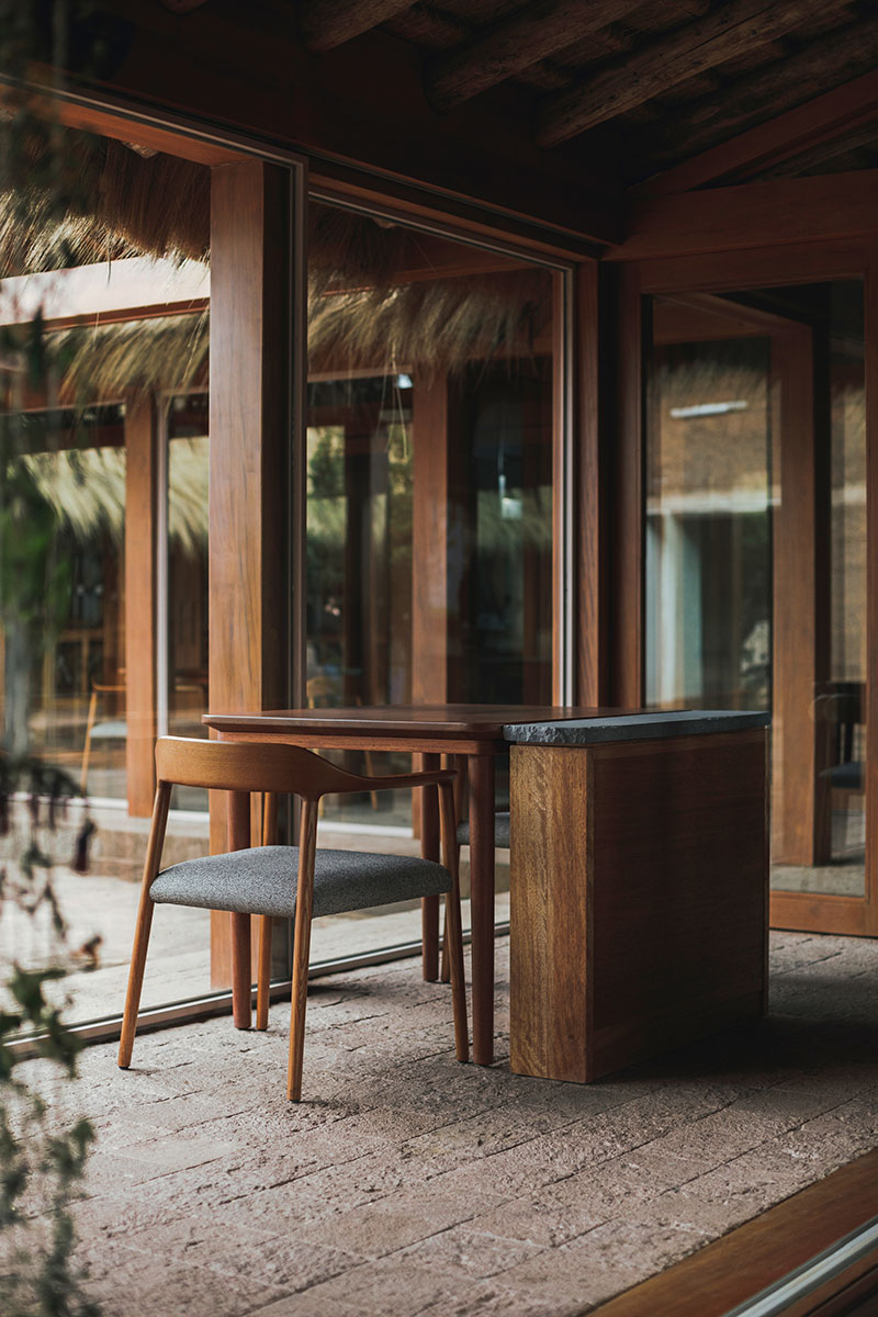 Mesa diseñada por Estudio Soroche en el restaurante Mil junto a cerramientos transparentes hacia el patio central