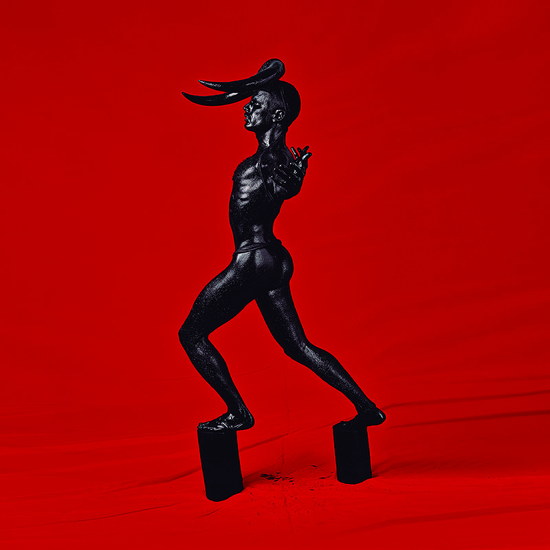 Imagen de persona vestida de negro con altos zuecos y fondo rojo