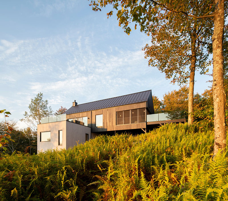 Fachada lateral de la residencia Le Noroît diseñada por Guillaume Pelletier Architecte vista desde la ladera