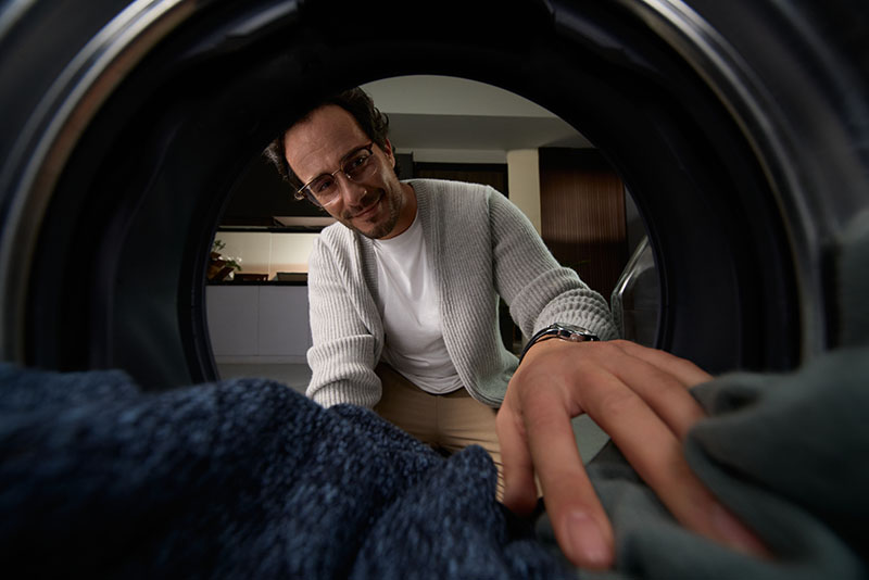 lavadora-secadora Roborock Zeo X: foto hecha desde el interior de la lavadora-secadora Roborock Zeo X abierta con un jomrbe de gafas con la mano dentro.