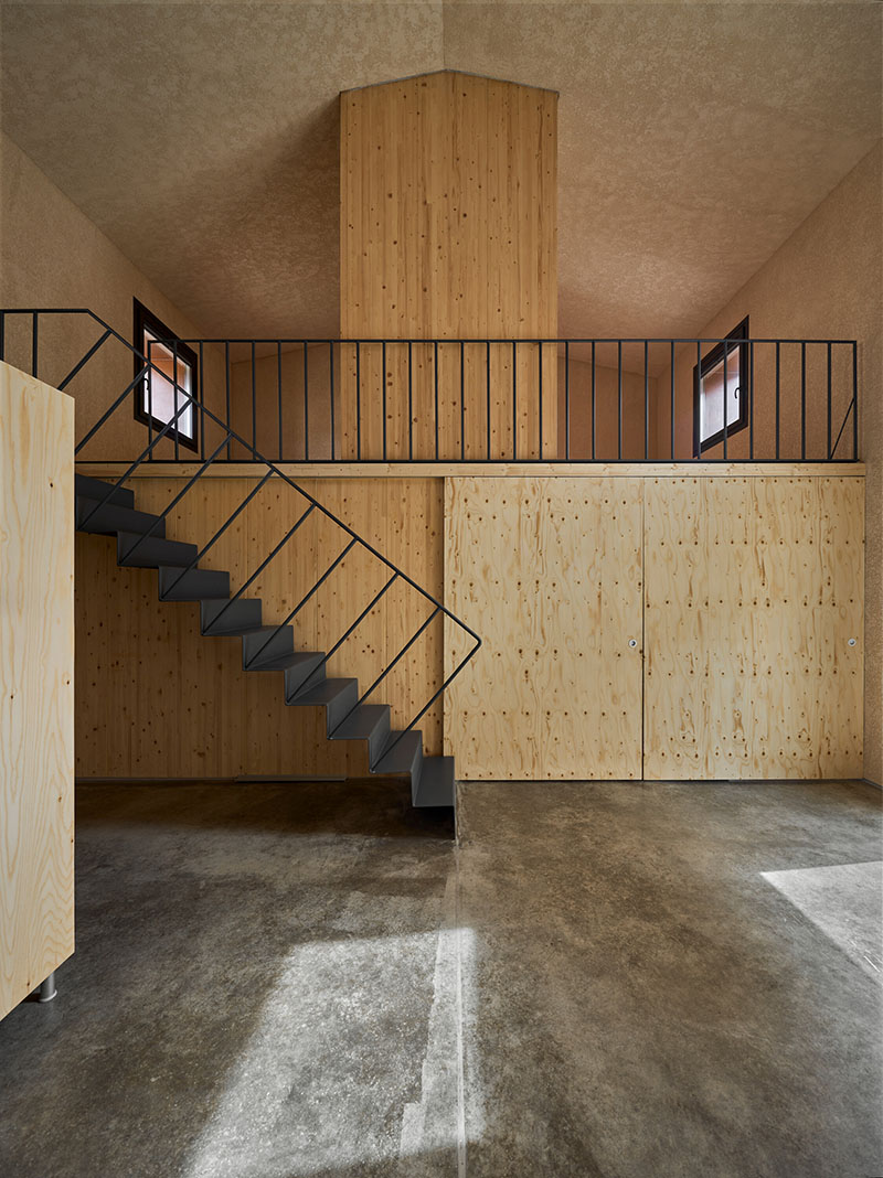 Interior con caja de madera y escalera metálica de Made V Arquitectos