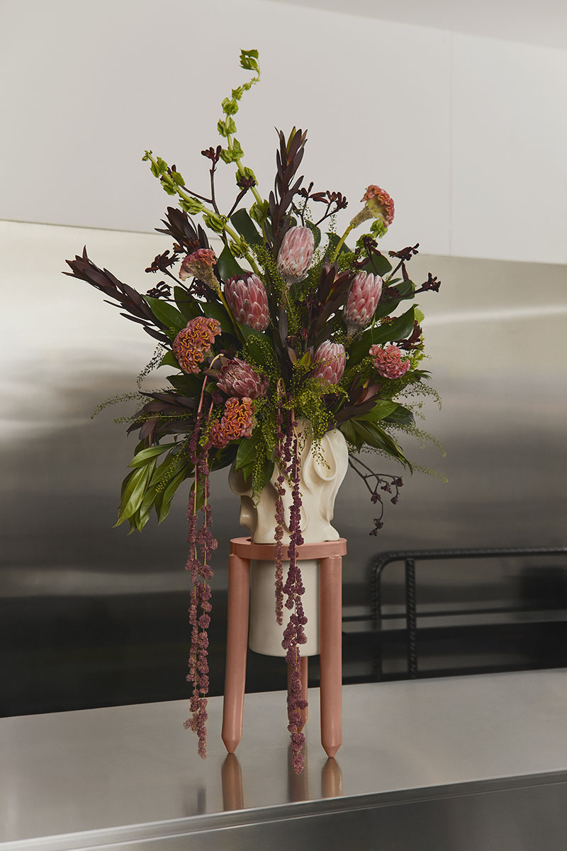 Florero de Ofenhaus con arreglo floral colocado sobre una mesa metálica