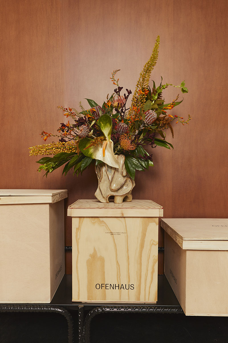 Florero escultórico de Ofenhaus con arreglo floral colocado sobre una caja de madera