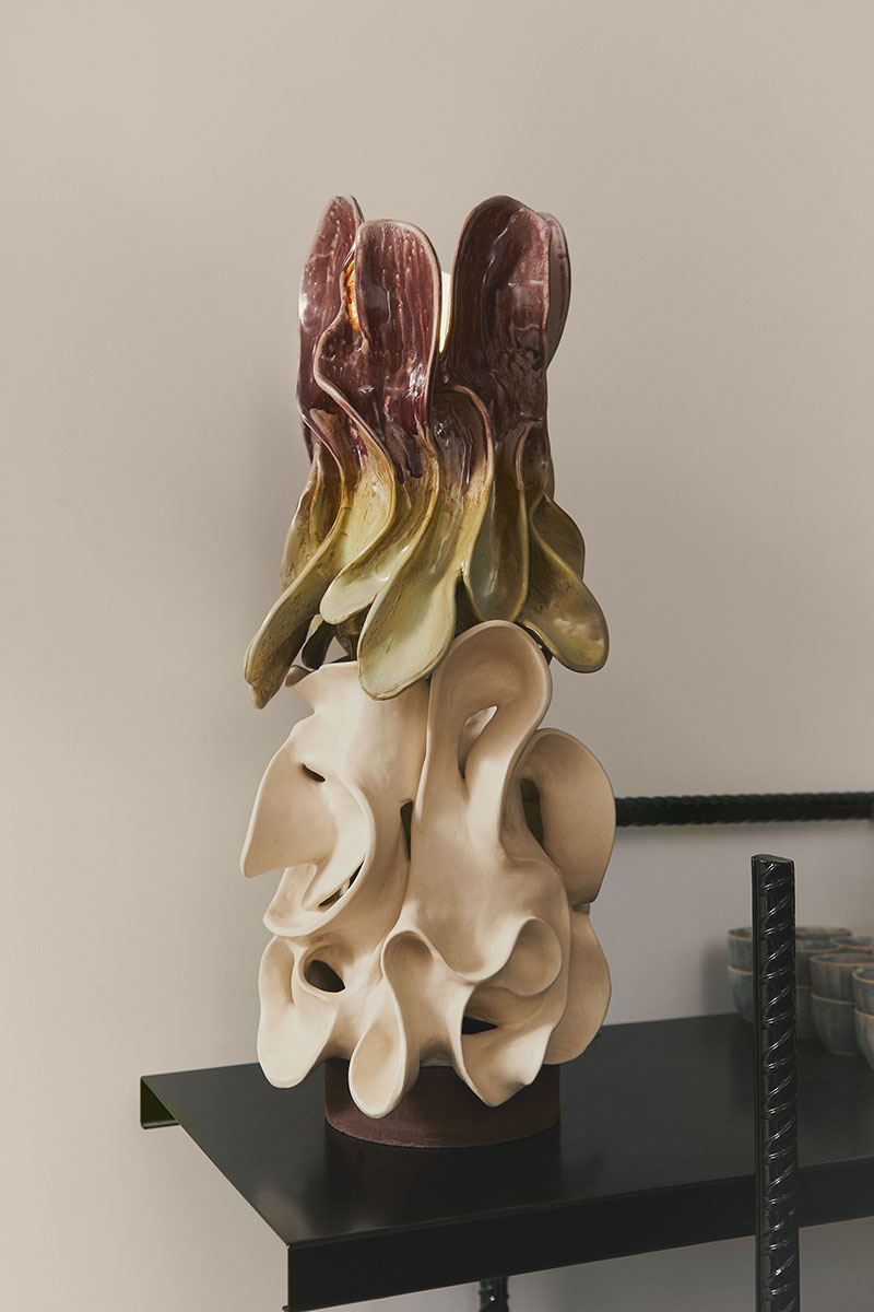 Escultura cerámica de Ofenhaus en tonos crema y granate exhibida en un estante