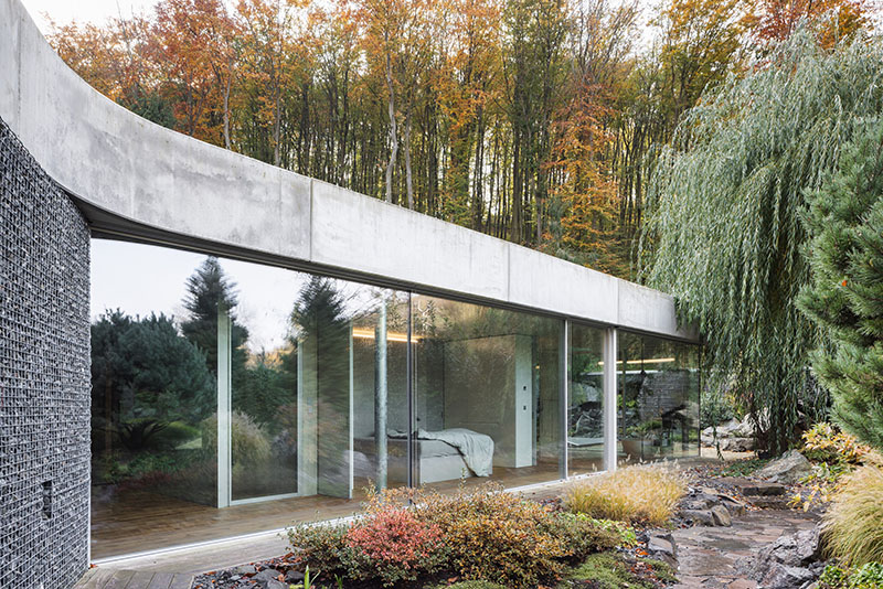 Dormitorio de Banánka de Paulíny Hovorka Architects con fachada acristalada hacia la arboleda