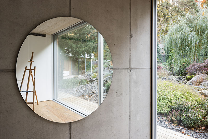 Interior de Banánka de Paulíny Hovorka Architects con espejo circular y vistas al jardín